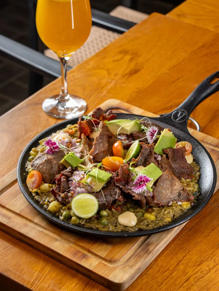 Arroz Moche con carnes secas, palta y flores comestibles en sartén de hierro